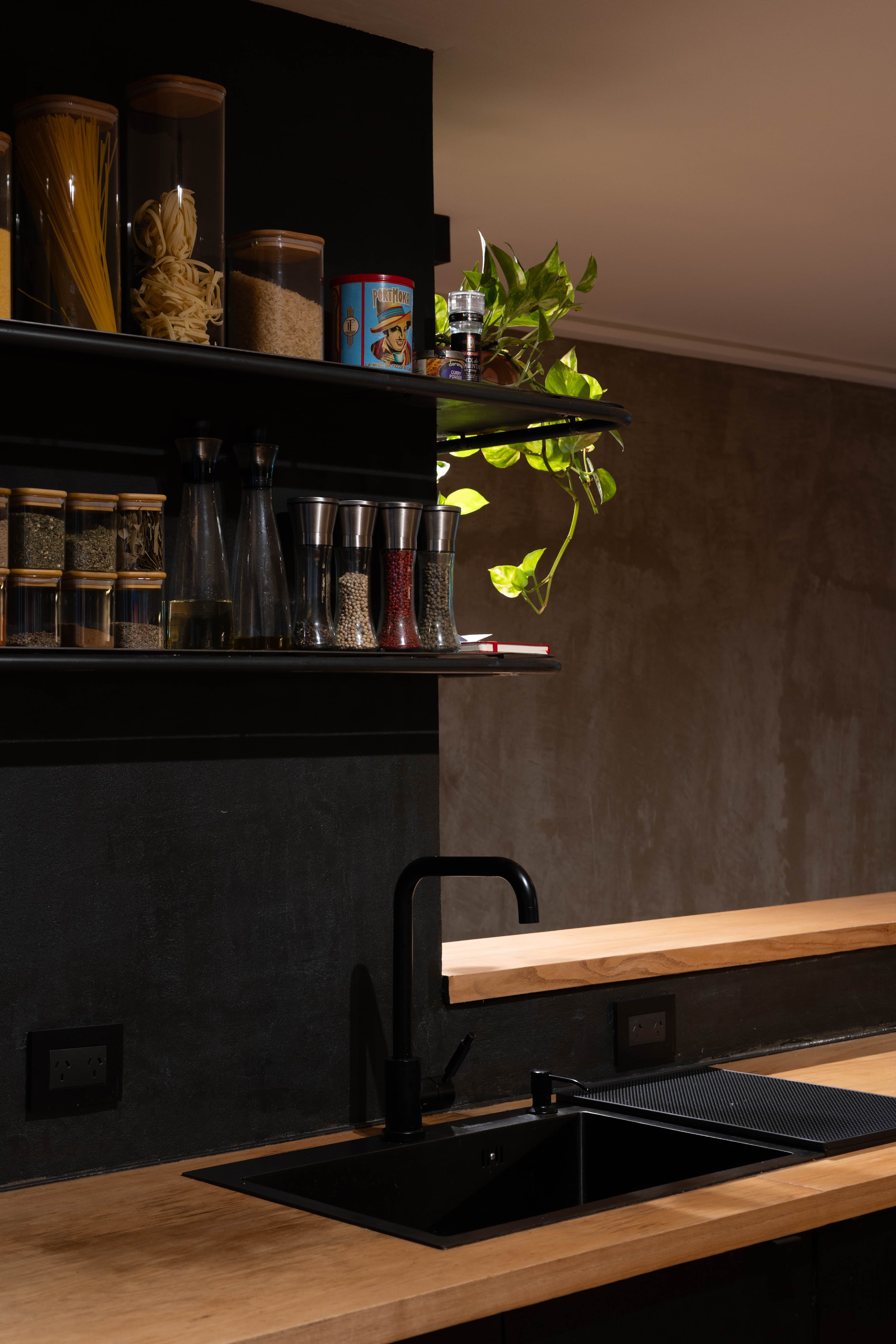 Detalle de la bacha negra, estanterías con especias y planta