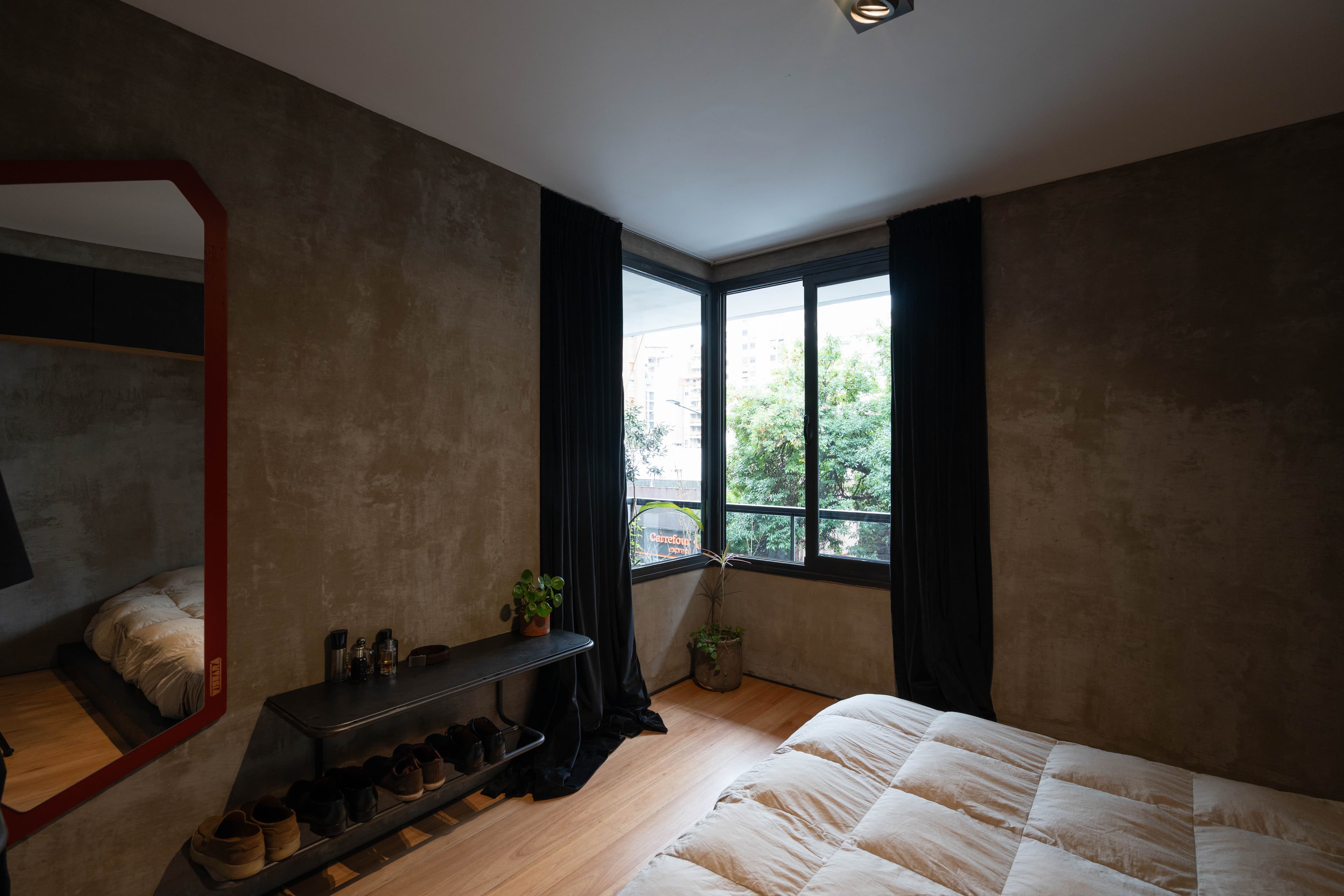 Habitación con cama doble, espejo y ventana con vista arbolada