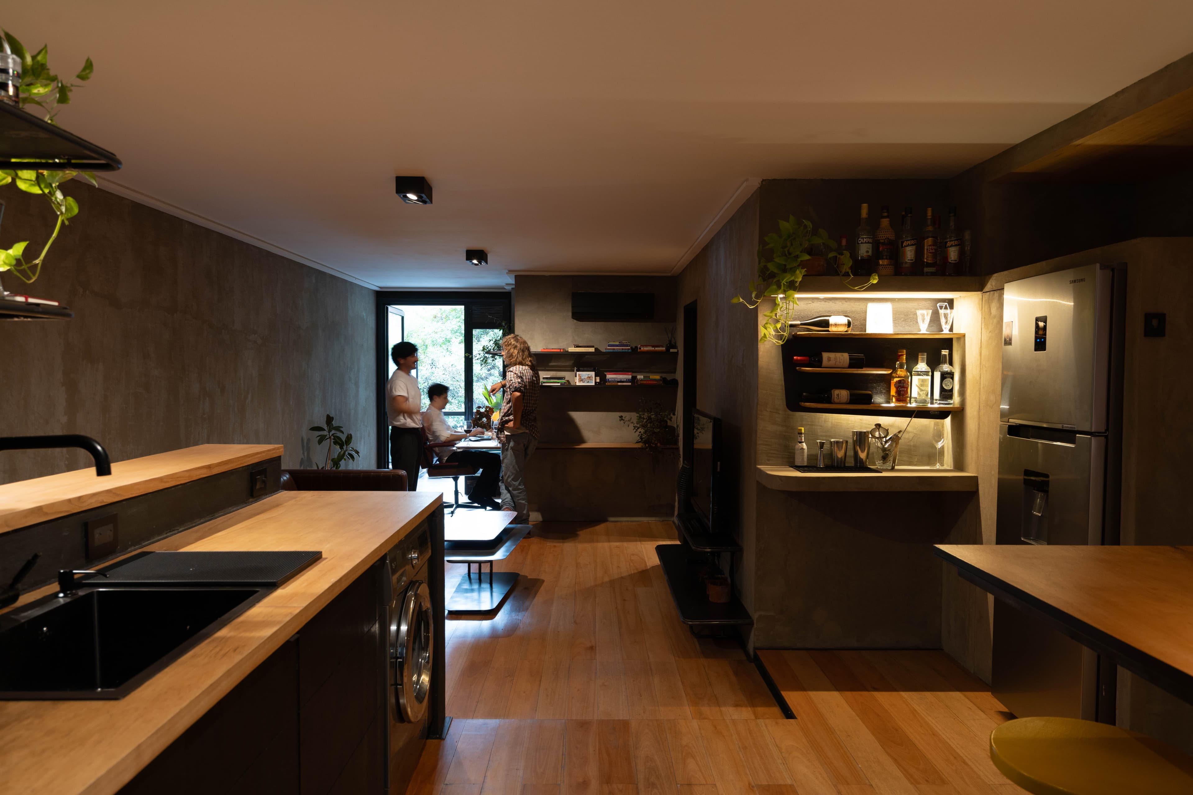 Vista del living desde la cocina con personas al fondo