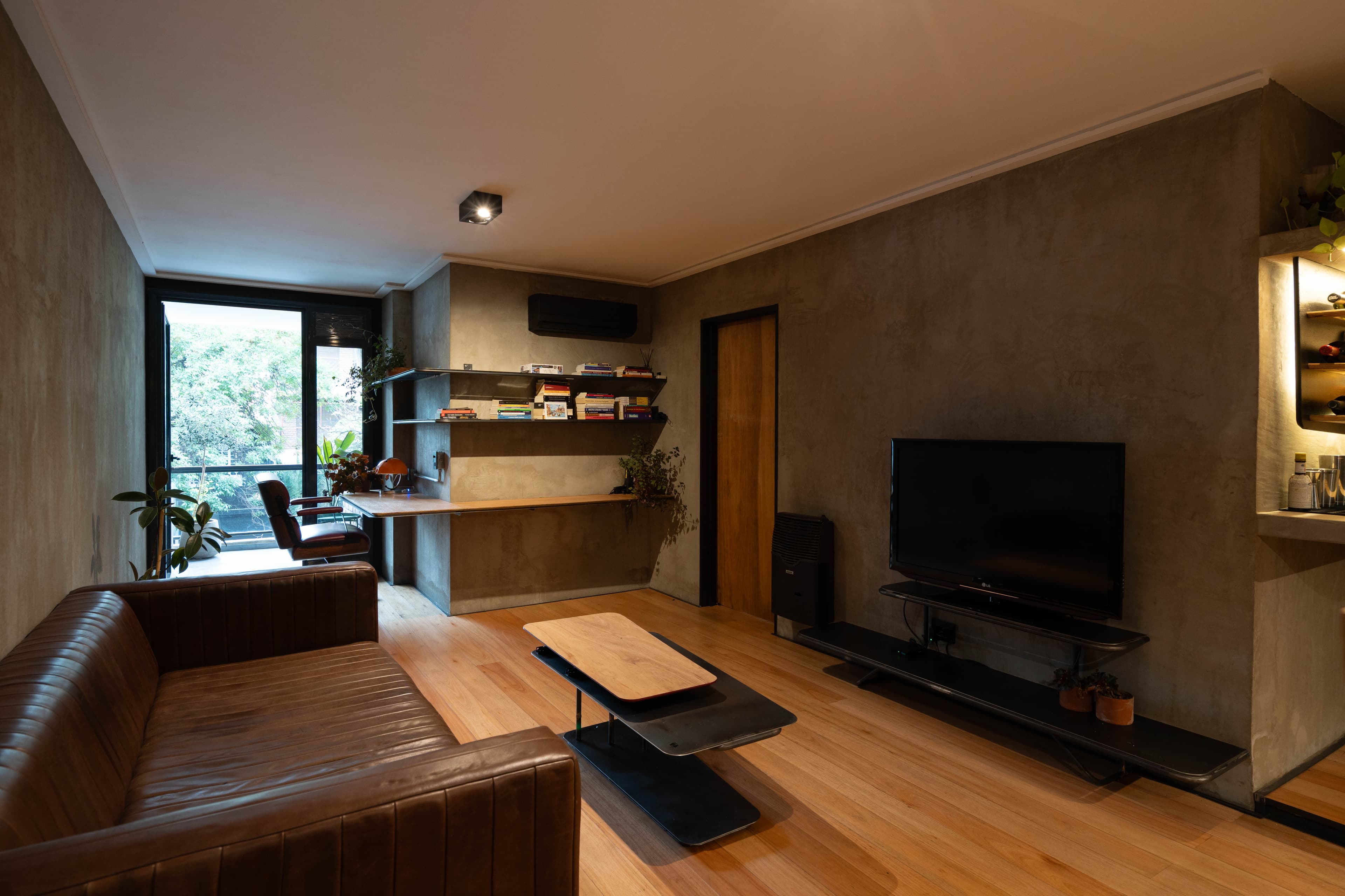 Living amplio con sillón de cuero, TV y zona de trabajo